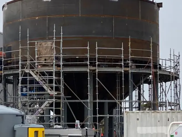 Original condition of a black steel water tank before treatment